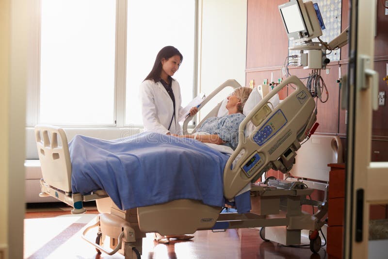 Kvinnlig kvinnlig patient för doktor Talks To Senior i sjukhussäng fotografering för bildbyråer