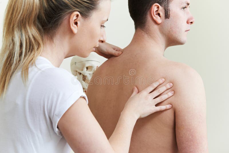 Kvinnlig osteopat som behandlar den manliga patienten med skuldraproblem royaltyfri bild Kvinnlig osteopat som behandlar den manliga patienten med skuldraproblem royaltyfri bild