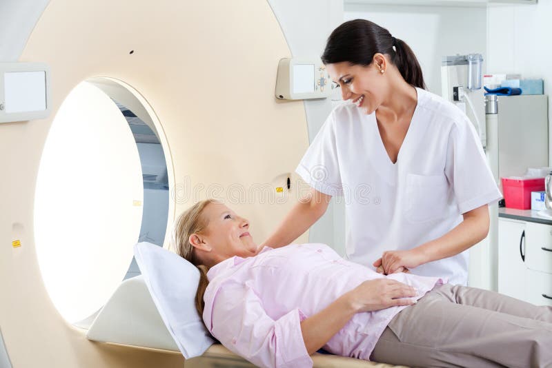 Radiologic technician smiling at mature female patient lying on a CT Scan bed. Radiologic technician smiling at mature female patient lying on a CT Scan bed