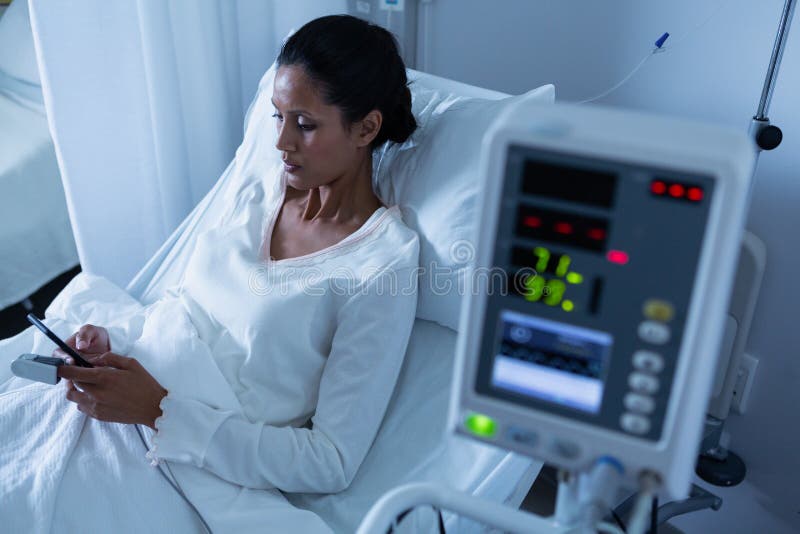 Kvinnlig patient som använder mobiltelefonen, medan koppla av på säng arkivfoton Kvinnlig patient som använder mobiltelefonen, medan koppla av på säng arkivfoton