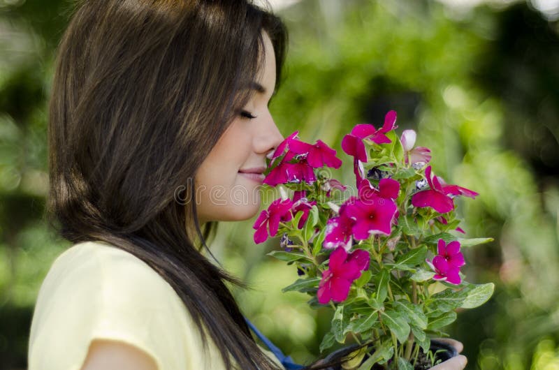 Kvinnlig trädgårdsmästare som luktar blommor arkivfoto Kvinnlig trädgårdsmästare som luktar blommor arkivfoto