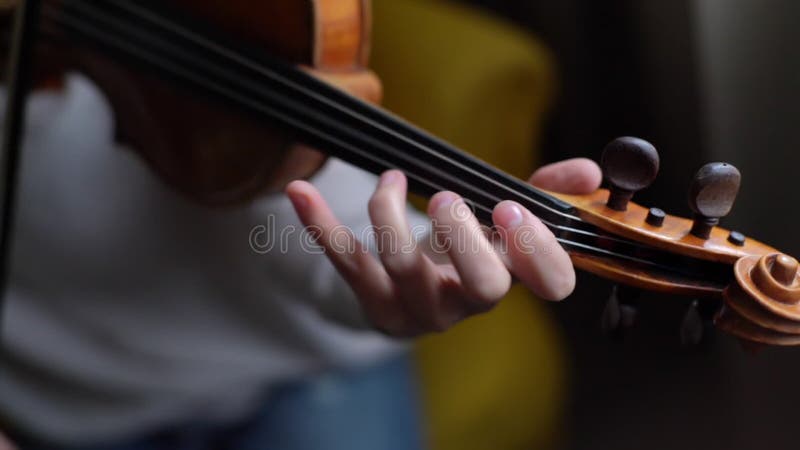 Kvinnlig violinmusiker som spelar hemma, nära i långsam rörelse