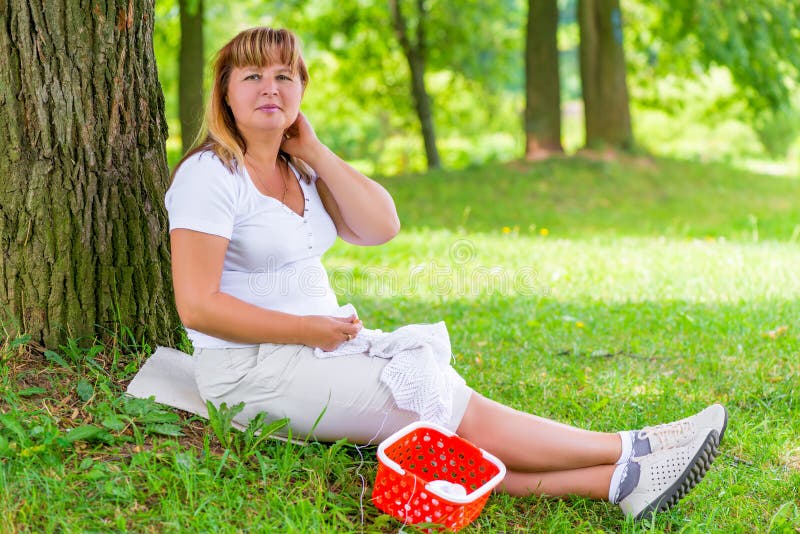 Female 50 years, does what he likes, is sitting near the tree. Female 50 years, does what he likes, is sitting near the tree