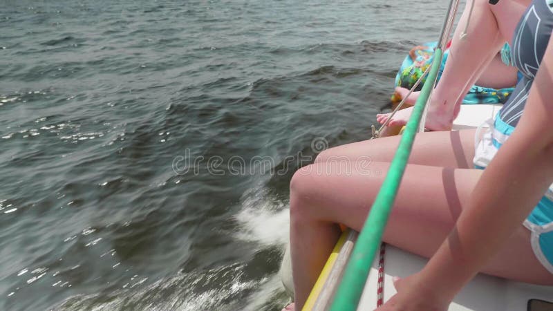 Kvinnliga ben som hänger över sida av den vita seglingyachten