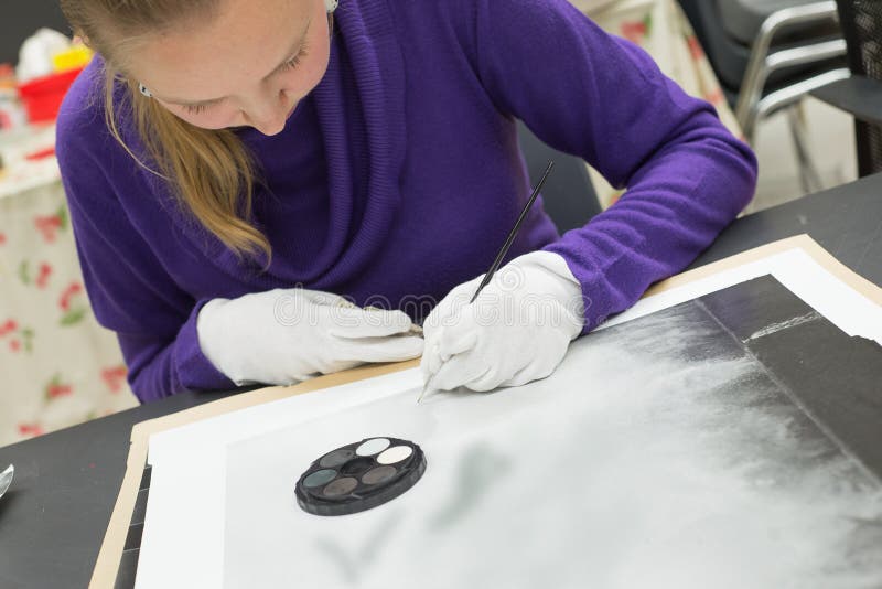 Kvinnliga blonda fotoretoucherkonstnärer som arbetar på för tryckfixande för analog konst svartvitt korn och skavanker royaltyfri fotografi Kvinnliga blonda fotoretoucherkonstnärer som arbetar på för tryckfixande för analog konst svartvitt korn och skavanker royaltyfri fotografi
