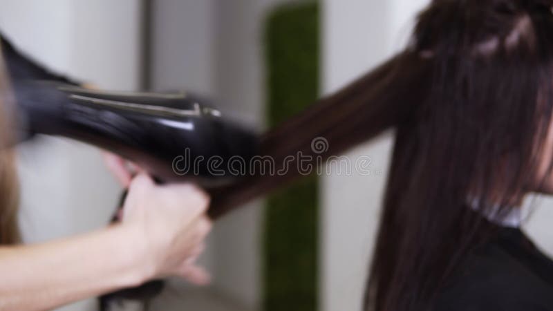 Kvinnliga frisörverktyg som torkar långa mörka hår från kvinnor som sitter i sallonstol Hårborttagare med fläkt och borsttorkning