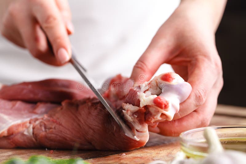 Kvinnliga händer med en kniv i deras hand klippte nytt kött på en tabell royaltyfria foton Kvinnliga händer med en kniv i deras hand klippte nytt kött på en tabell royaltyfria foton