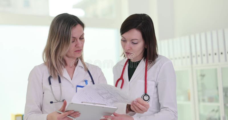 Kvinnliga läkare undersöker patientens sjukdomshistoria på klinik lager videofilmer
