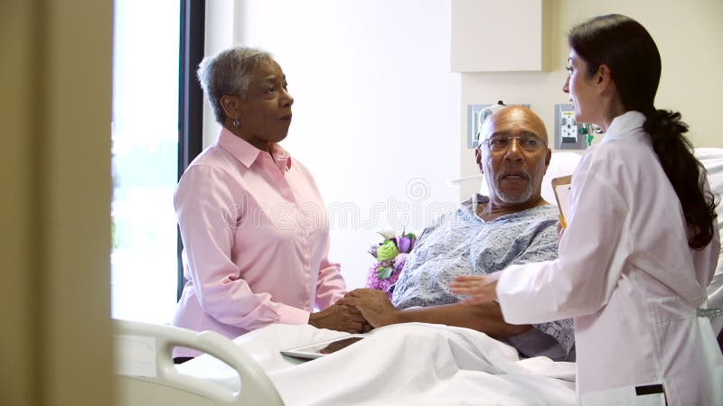 Kvinnliga par för doktor Talking To Senior i sjukhusrum lager videofilmer