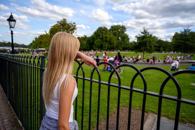 Kvinnliga turister som tittar på människor som leker i vattnet i Diana Memorial Fountain, Hyde Park, London, England royaltyfri bild Kvinnliga turister som tittar på människor som leker i vattnet i Diana Memorial Fountain, Hyde Park, London, England royaltyfri bild