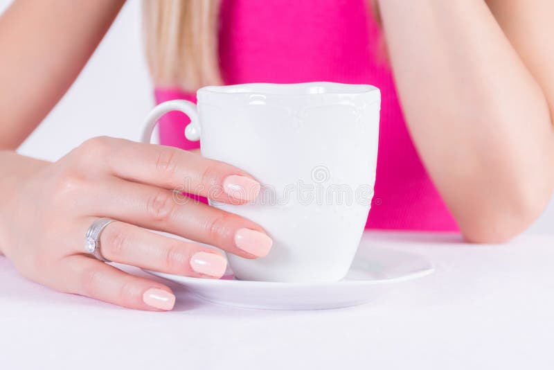 Kvinnlign med näck färgmanikyr spikar polermedel stelnar och diamantcirklar på den hållande kaffekoppen för fingret arkivfoto Kvinnlign med näck färgmanikyr spikar polermedel stelnar och diamantcirklar på den hållande kaffekoppen för fingret arkivfoto
