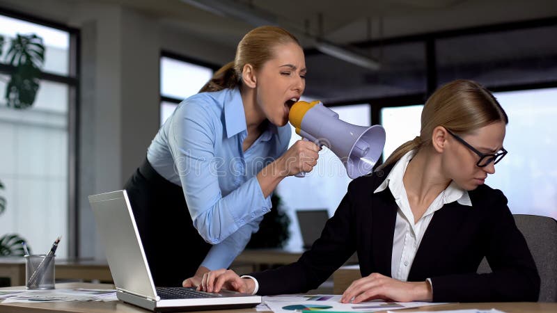 Female boss screaming with megaphone at colleague, authoritarian leadership, stock photo. Female boss screaming with megaphone at colleague, authoritarian leadership, stock photo