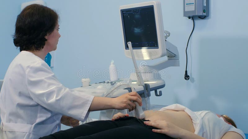 Kvinnligt sätta för doktor stelnar på den tålmodiga magen för ultraljudsundersökning arkivfoto Kvinnligt sätta för doktor stelnar på den tålmodiga magen för ultraljudsundersökning arkivfoto