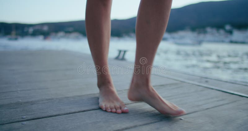 Kvinnopromenad barefoot på strandpromenad