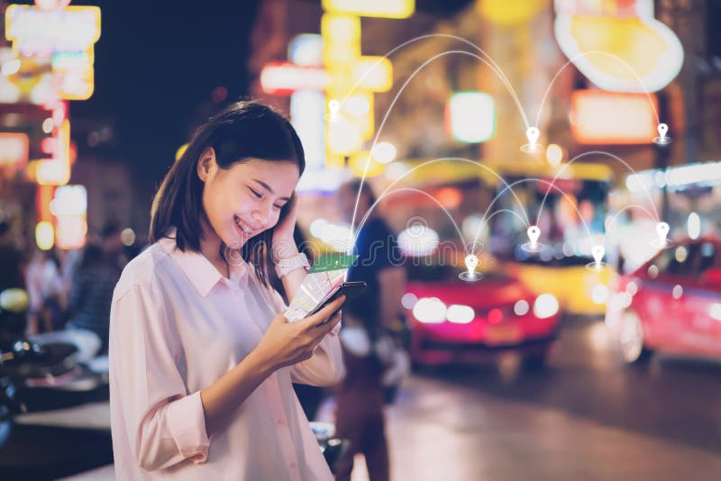 Women use smartphone at night on city shopping street, and use the map application in navigation. Women use smartphone at night on city shopping street, and use the map application in navigation