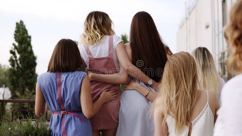 kvinnor för kamratskap s Den blonda flickan är stående near balkongräcke och att se framåtriktat Flickvänner är kommande till hen