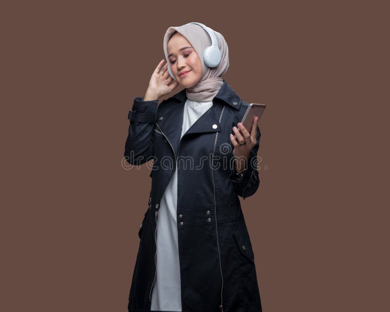 Kvinnor i hijab lyssnar på musik från sin mobiltelefon med trådlösa hörlurar fotografering för bildbyråer
