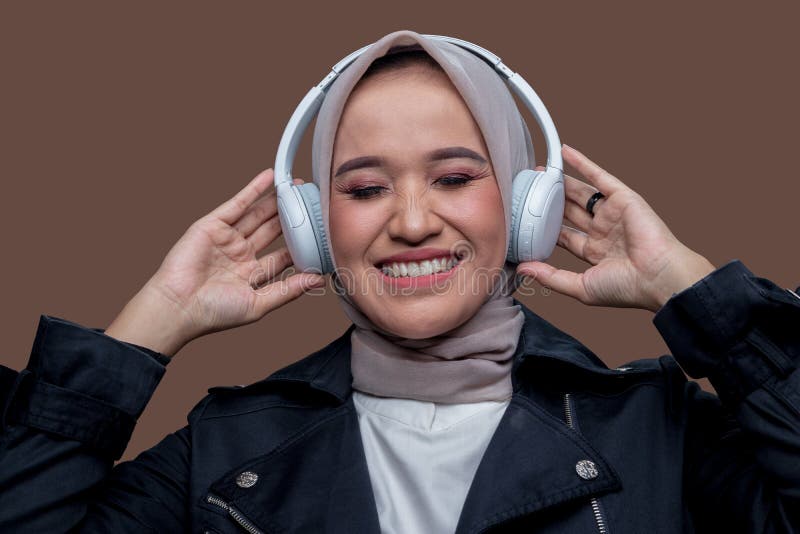Kvinnor i hijab som har trådlös hörlurar med leende medan hon blundar arkivfoto