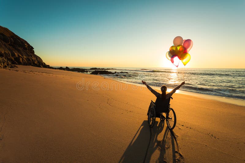 Handicapped woman on a wheelchair with colored balloons at the beach. Handicapped woman on a wheelchair with colored balloons at the beach