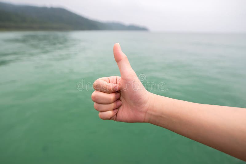 Kvinnor räcker med tummen upp på det gröna havet fotografering för bildbyråer Kvinnor räcker med tummen upp på det gröna havet fotografering för bildbyråer