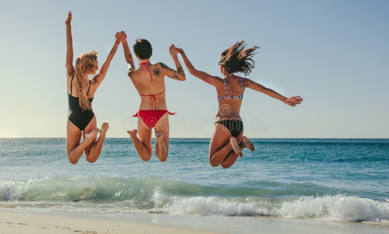 Kvinnor som hoppar i luft och tycker om på stranden arkivfoton Kvinnor som hoppar i luft och tycker om på stranden arkivfoton