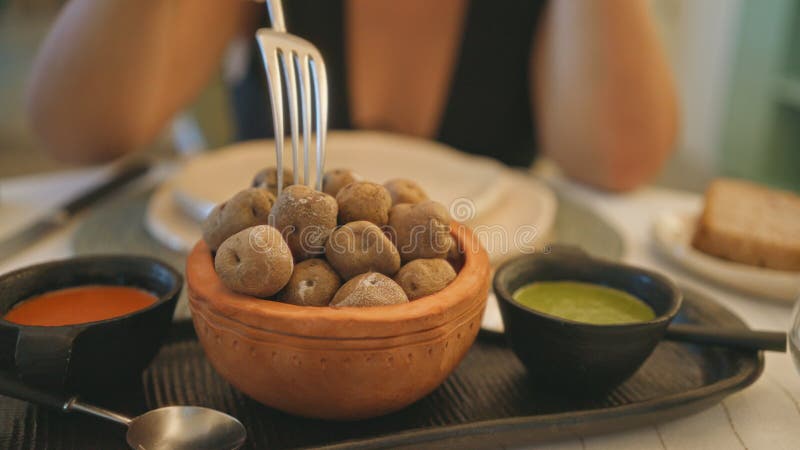 Kvinnor som njuter av papas arrugadas i en fin restaurang inomhus med dippsåser och eleganta bordsartiklar fotografering för bildbyråer