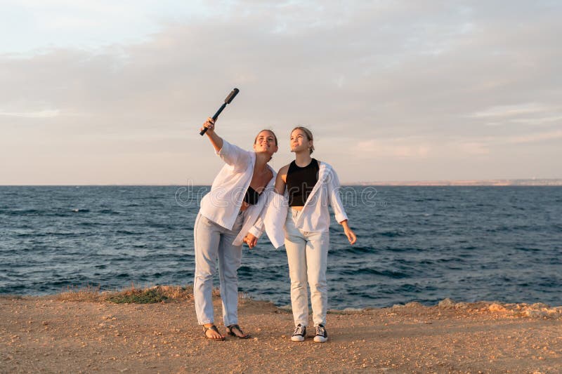 Kvinnor som solnedgång i strand två kvinnor tar en selfie på en strand vid solnedgången. arkivfoto