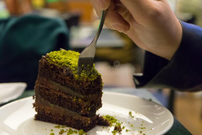 Kvinnor som äter chokladkaka med pistaschmandlar och tar en bit på en kokt efterrätt i en restaurang Handtag med Fork-smak arkivbilder Kvinnor som äter chokladkaka med pistaschmandlar och tar en bit på en kokt efterrätt i en restaurang Handtag med Fork-smak arkivbilder