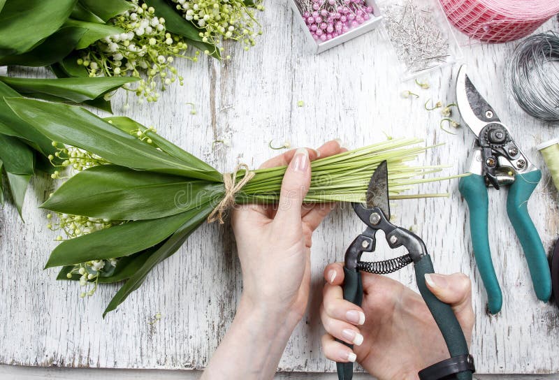 Florist at work. Woman making bouquet of lily of the valley flowers. Festive and party decoration. Florist at work. Woman making bouquet of lily of the valley flowers. Festive and party decoration