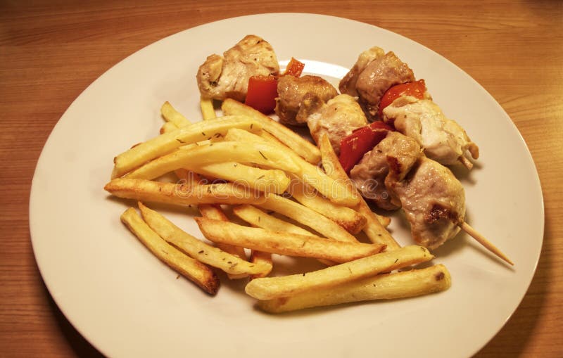 Kycklingkött på träskal på vit plåt med fransfrites royaltyfri foto Kycklingkött på träskal på vit plåt med fransfrites royaltyfri foto