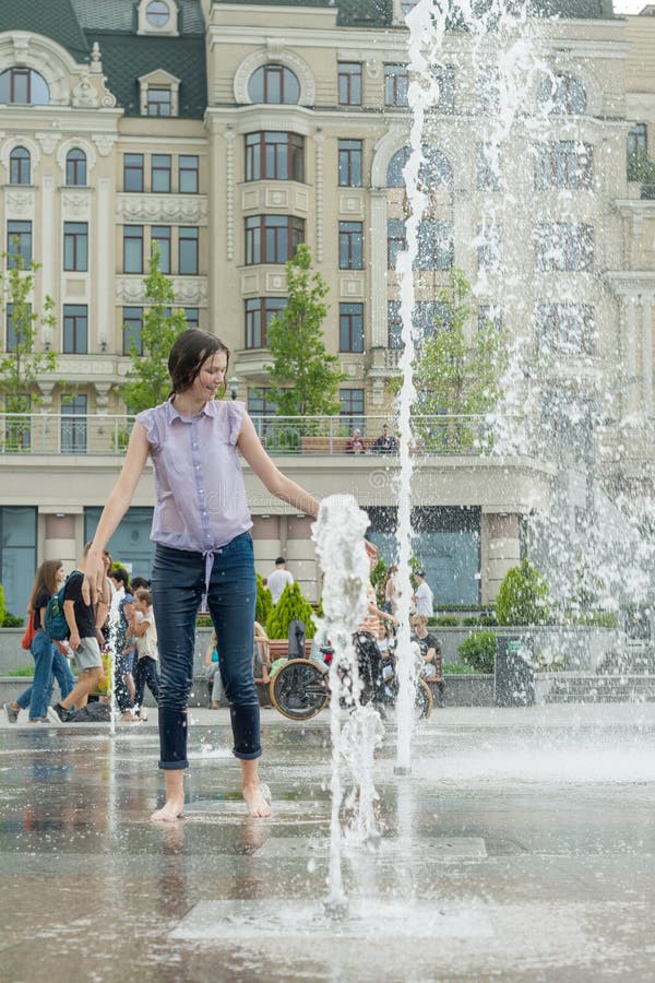 Kyiv uA, 19-07-2018 La giovane ragazza teenager allegra in fontana della città, ragazza in vestiti bagnati è divertentesi e goden fotografia stock libera da diritti Kyiv uA, 19-07-2018 La giovane ragazza teenager allegra in fontana della città, ragazza in vestiti bagnati è divertentesi e goden fotografia stock libera da diritti