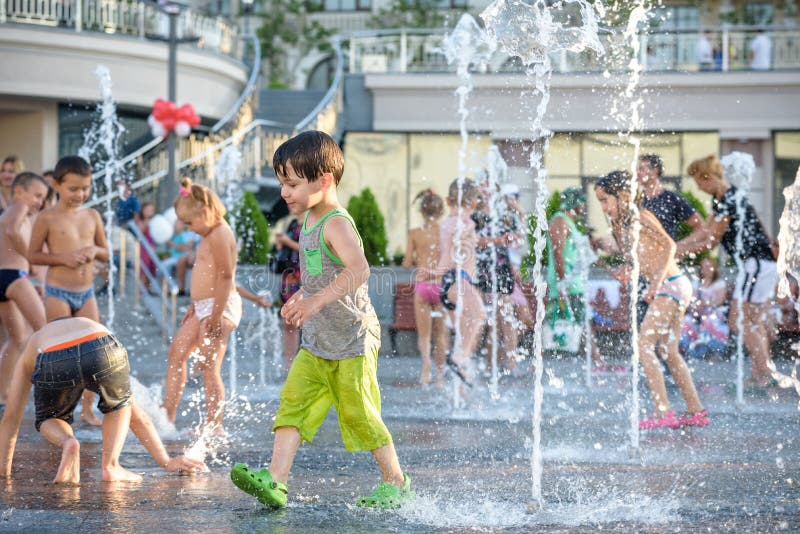 KYIV, UKRAINE AUGUST 13, 2017: Happy kids have fun playing in city water fountain on hot summer day.