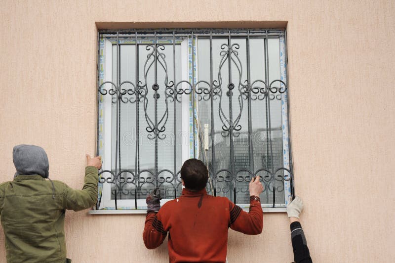 KYIV, UKRAINE - oktober, 2019: Arbetarinstallationsfönstrets järnsäkerhetsfält för hussäkerhet Kontraktorer för installation av f arkivfoto KYIV, UKRAINE - oktober, 2019: Arbetarinstallationsfönstrets järnsäkerhetsfält för hussäkerhet Kontraktorer för installation av f arkivfoto