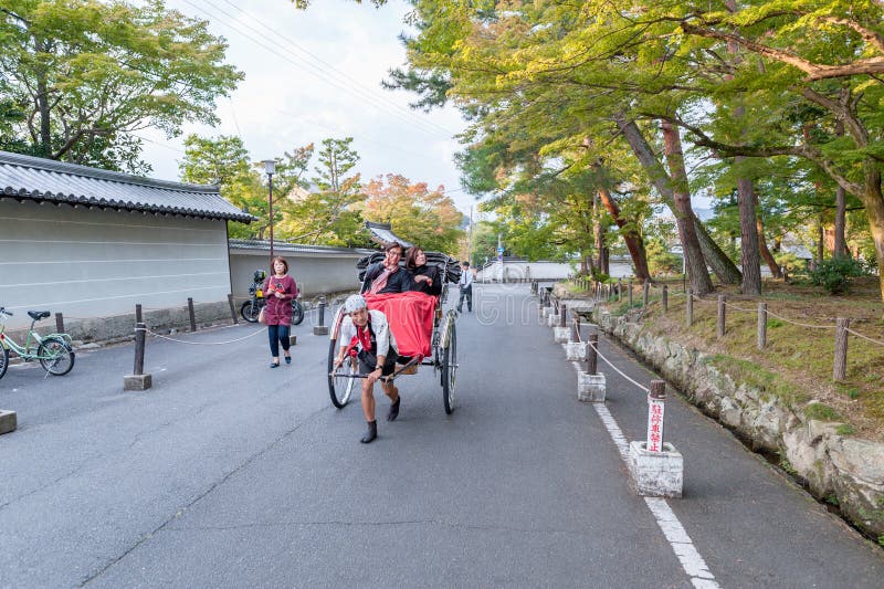 KYOTO JAPAN - OKTOBER 08, 2015: Rickshaw i Tokyo, Japan Med lokalen Poople och Shite parkera i bakgrund arkivfoto KYOTO JAPAN - OKTOBER 08, 2015: Rickshaw i Tokyo, Japan Med lokalen Poople och Shite parkera i bakgrund arkivfoto
