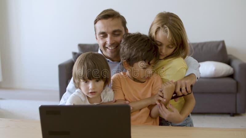 Kärleksfull far som gillar barn och tittar på skärmen på den bärbara datorn