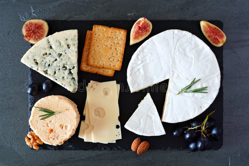 Käsebrett mit einer Auswahl an Käse, Knacken, Feigen und Nüssen, über dem Blick auf eine Tafel mit Schiefer lizenzfreie stockbilder