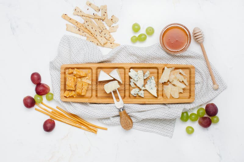 Käseplatte nahe Trauben, Honig und Cracker auf weißem Marmorhintergrund stockbild Käseplatte nahe Trauben, Honig und Cracker auf weißem Marmorhintergrund stockbild