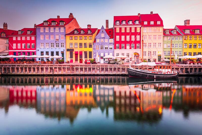 Copenhagen, Denmark. Nyhavn, Kobenhavn's iconic canal, reflects colorful buildings and glowing streetlights at twilight, creating a picturesque tourist destination. Copenhagen, Denmark. Nyhavn, Kobenhavn's iconic canal, reflects colorful buildings and glowing streetlights at twilight, creating a picturesque tourist destination