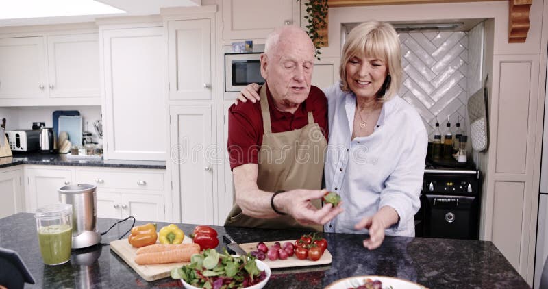 Köksmatning och gammal man i undervisningskvinnan för att göra sallad kärlek och lycka vid pensionering med hälsosam mat. Glad stock video