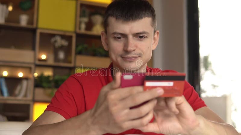 Köpandegods för ung man från internet på hans smartphone med hans kreditkort lager videofilmer
