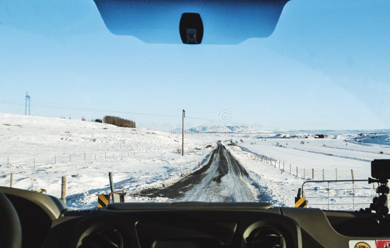 Körning på landsvägen i vinter Se till och med bilframdelvindrutan, täckte gör klar den fryste vägen med snö och blå himmel in I arkivfoton Körning på landsvägen i vinter Se till och med bilframdelvindrutan, täckte gör klar den fryste vägen med snö och blå himmel in I arkivfoton