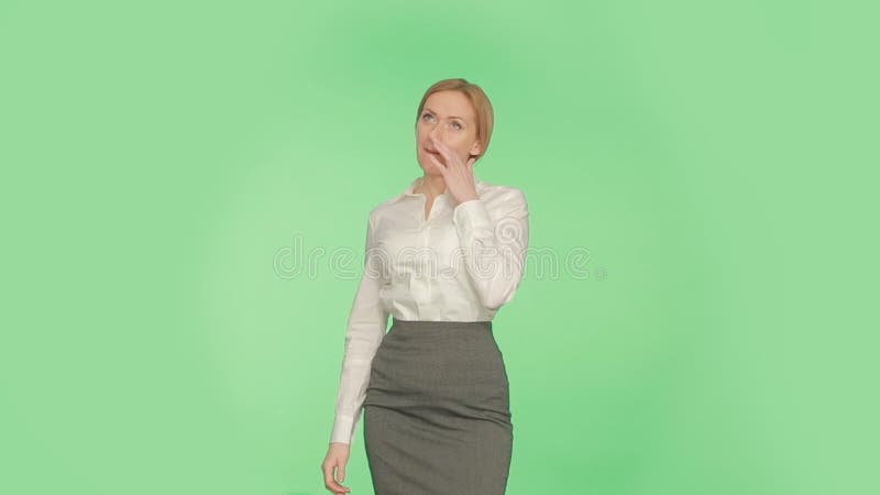 Körpersprache Schönes blondes Mädchen in einer weißen Bluse auf einem grünen Hintergrund