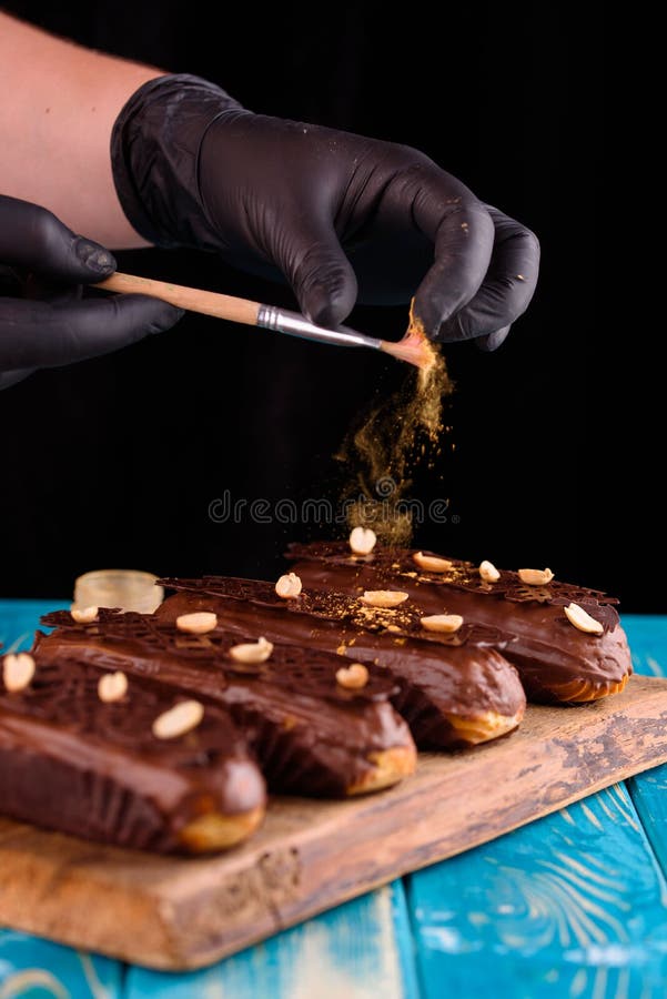 Köstliche Schokolade und Erdnuss Eclairs auf einem blauen Holztisch lizenzfreie stockbilder Köstliche Schokolade und Erdnuss Eclairs auf einem blauen Holztisch lizenzfreie stockbilder