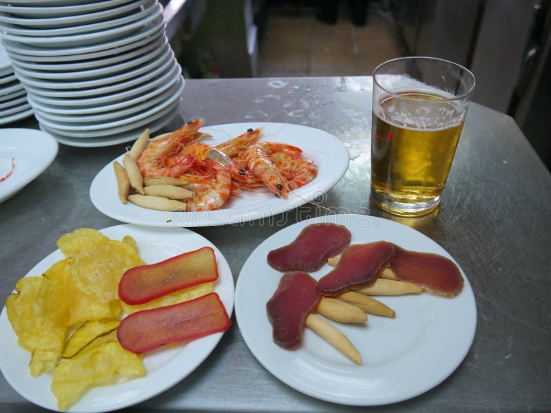 Köstliche Tapas auf weißen Platten und einem Glas Bier stockbilder Köstliche Tapas auf weißen Platten und einem Glas Bier stockbilder