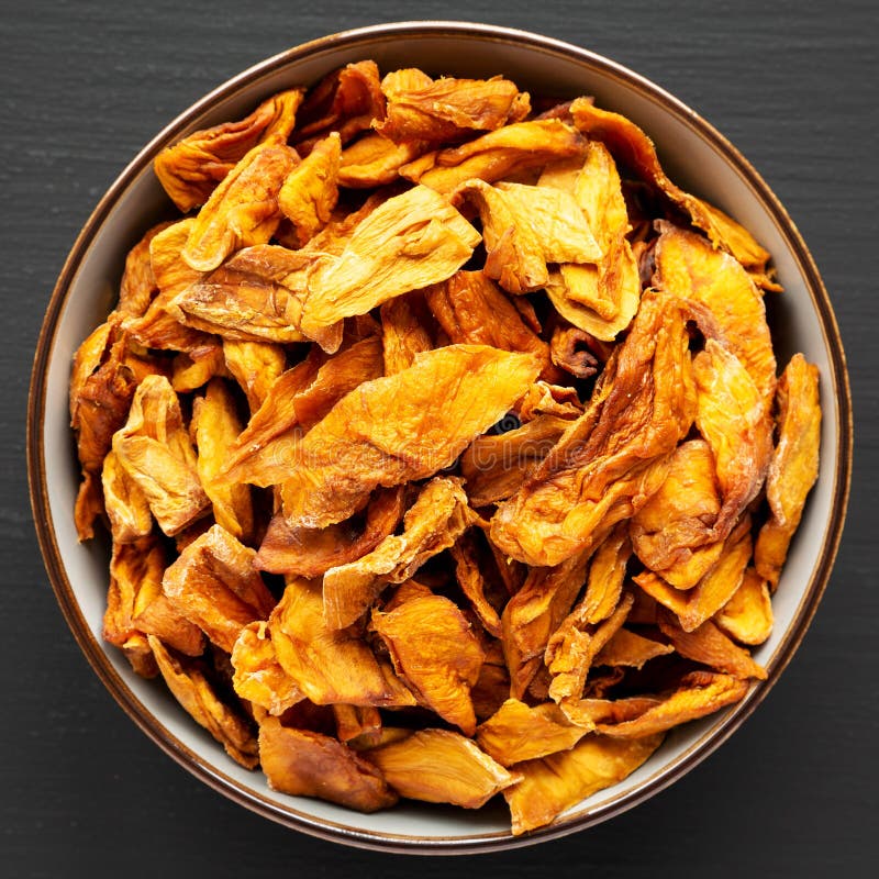 Köstliche, ökologisch getrocknete Mango-Früchte in einer Schüssel auf schwarzem Hintergrund oben Ansicht. flache Deckschicht von oben.