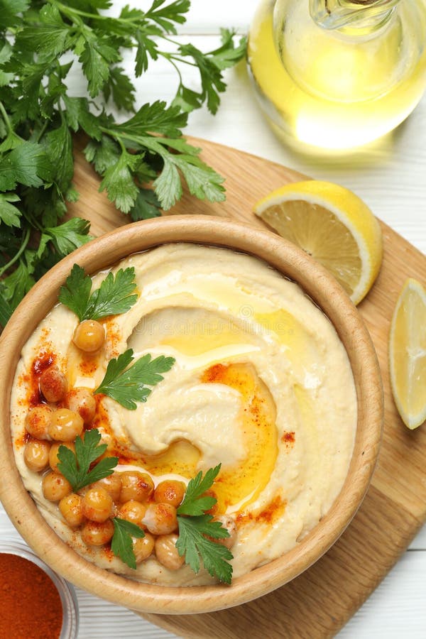 Köstlicher Hummus mit Olivenölkichererbsen und Petersilie auf weißem Holztisch flach stockfotografie