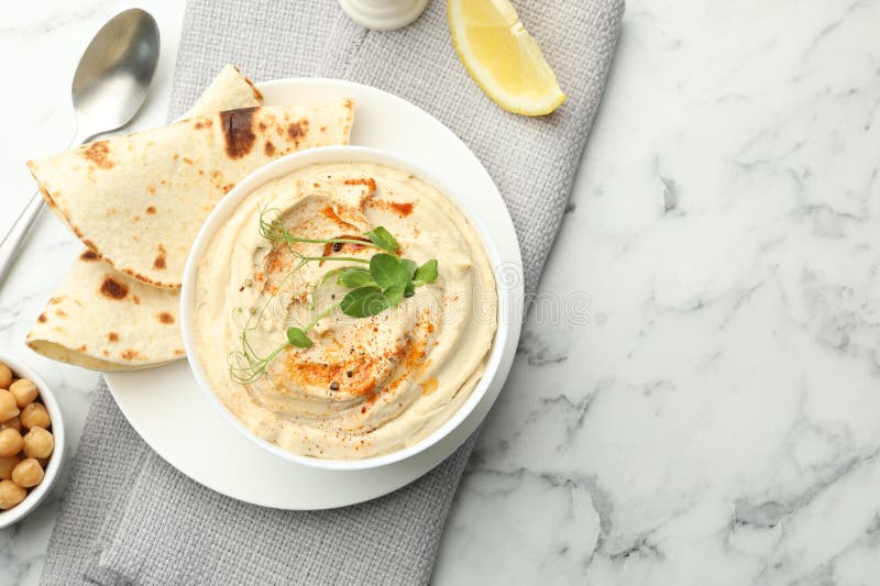 Köstlicher Hummus mit Paprika-Pita und Kichererbsen auf weißem Marmortisch, Topansicht. Platz für Text lizenzfreie stockbilder