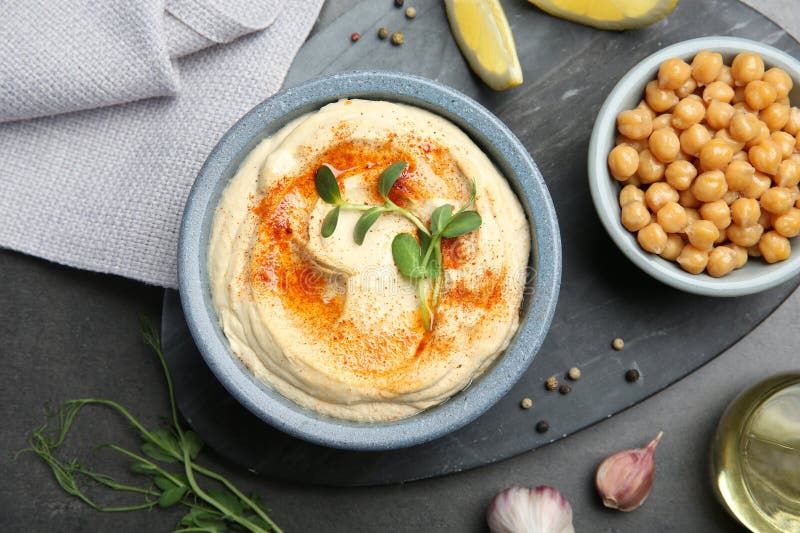 Köstlicher Hummus mit Paprika und Kichererbsen, serviert auf dunkelgrauem Tischflach stockbild