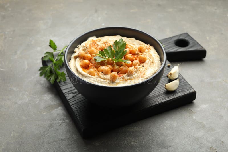 Köstlicher Hummus mit Petersilie Paprika und Kichererbsen auf grauem Tisch stockbild