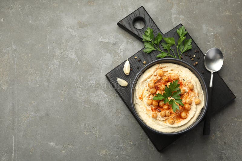 Köstlicher Hummus mit Petersilie Paprika und Kichererbsen auf grauem Tischspiegel. Platz für Text lizenzfreies stockbild